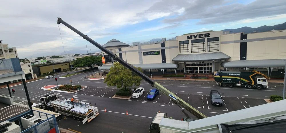 Crane lifting sequenced roofing material packs at Mid-City Apartments