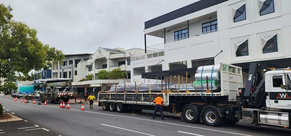 Early-morning roofing material delivery under traffic management on McLeod Street